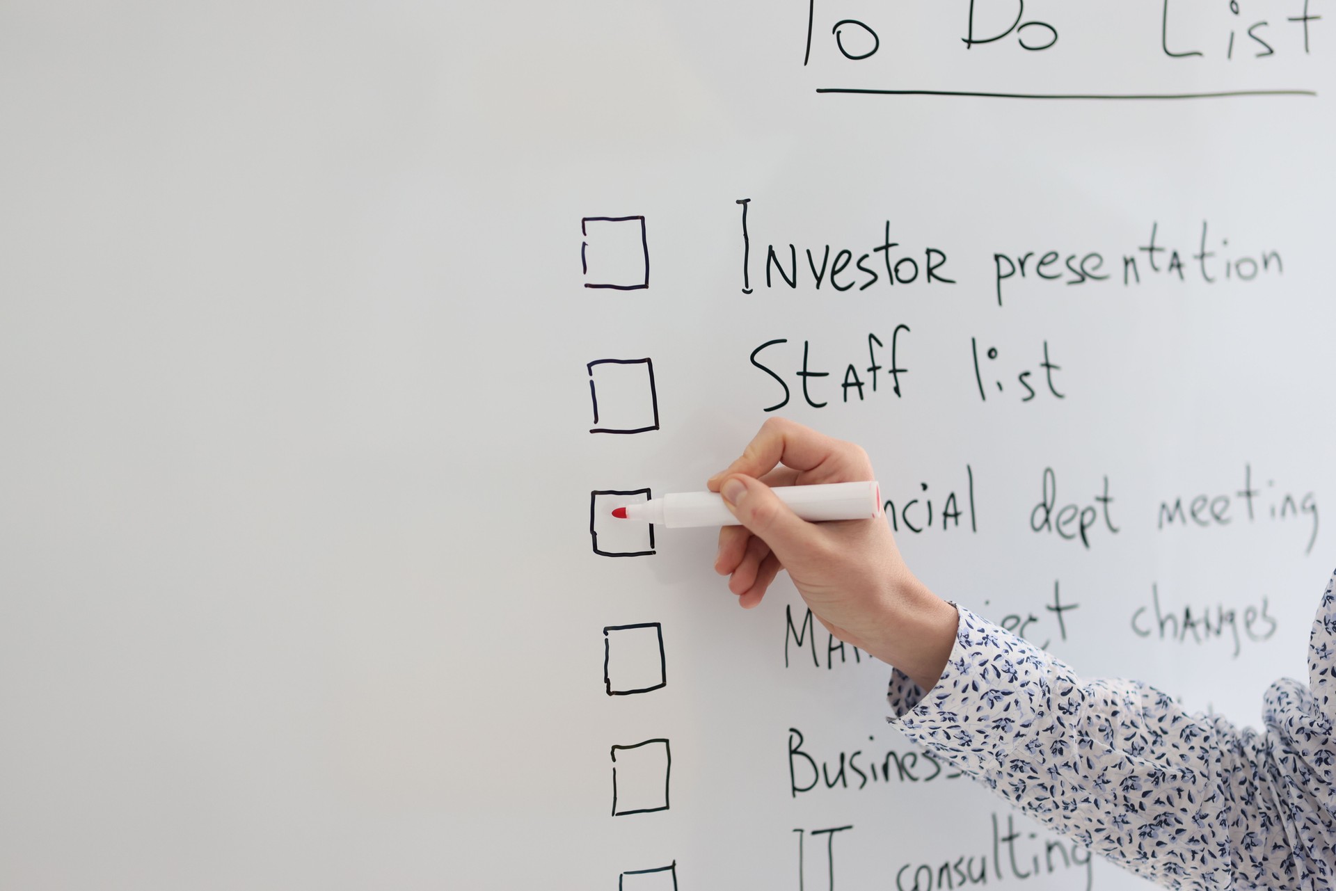 Female worker marks schedule points written on whiteboard